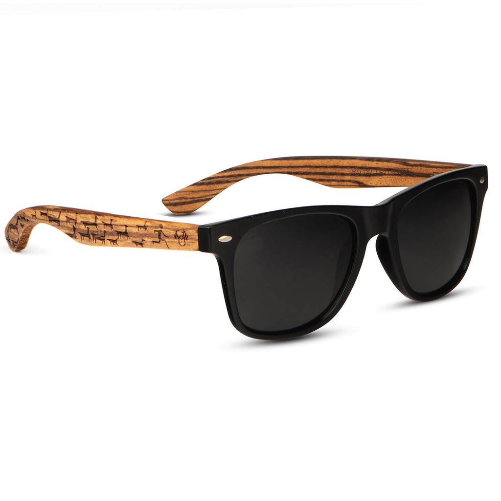 anteojos o gafas de sol polarizadas de color negro con patas o varillas de madera natural reciclada sustentable. Vista angulada madera de zebrano y anteojo o marco de color negro polarizado para hombre y mujer