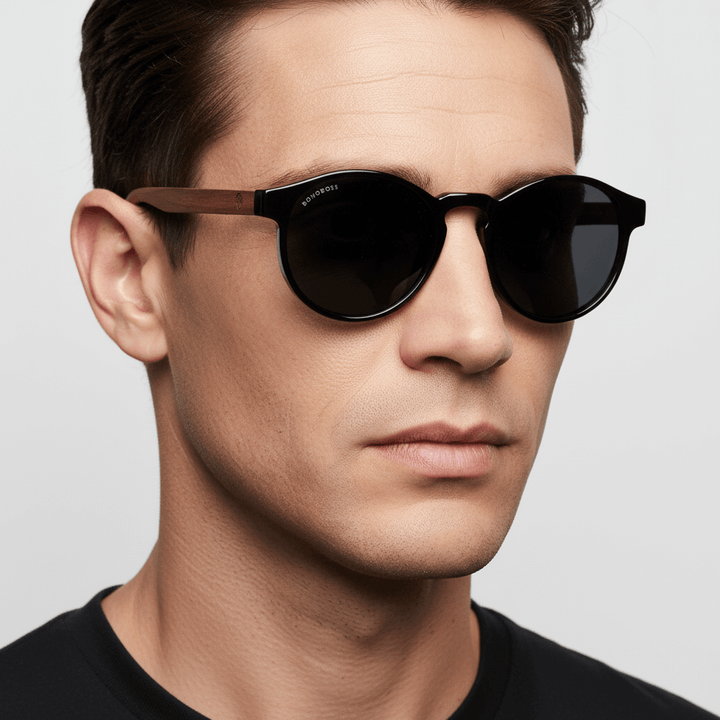 Angled view a modelo men cara ovalada wearing unos eyeglasses sunglasses polarized forma redonda and with puente for narices anchas hechas recycled plastic sustainable ecologico personalizada de Bonoboss #color_negro