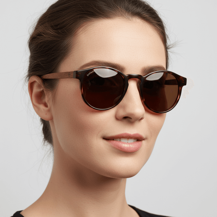 Side view a modelo women cara ovalada wearing unos eyeglasses sunglasses polarized forma redonda and with puente for narices anchas hechas recycled plastic sustainable ecologico personalizada and wooden temples de Bonoboss #color_carey