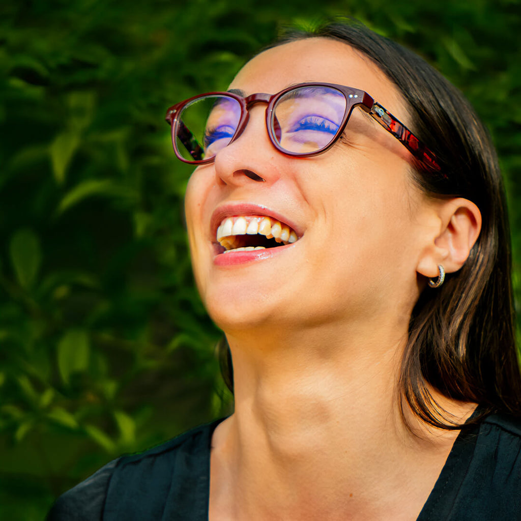 mujer de cara ovalada usando anteojos de lectura de color rojo y de forma redonda