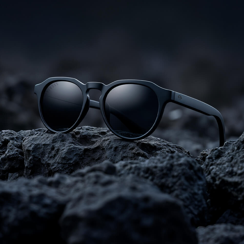 anteojos de sol polarizados de color negro en sobre rocas negras y el reflejo de la luz en ellos una foto increible de catalogo #color-marco_negro